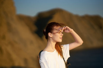 Young woman looking away against sky