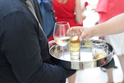 Midsection of waiter serving drinks to people