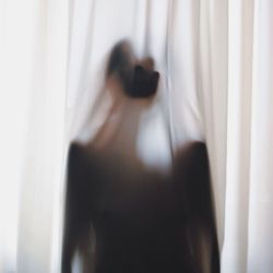 Close-up of woman standing against white wall