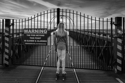 Rear view of woman on bridge against sky