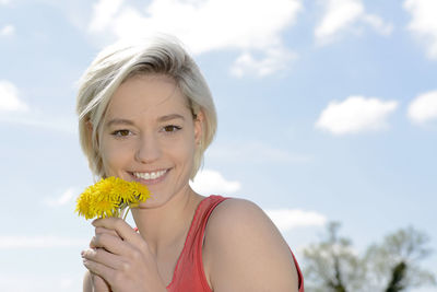 Portrait of smiling young woman against blue sky