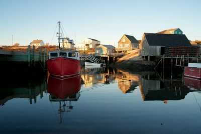 Boats moored at harbor against clear sky