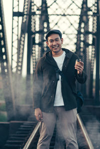 Portrait of young man standing on railroad track