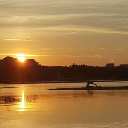 Silhouette person on shore against sky during sunset