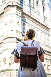 Rear view of woman standing against building in city