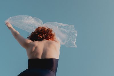 Rear view of woman standing against blue sky