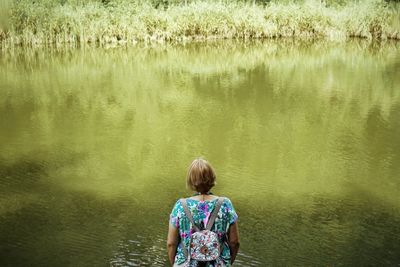 Rear view of boy standing in lake