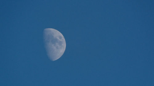 Low angle view of moon against clear blue sky