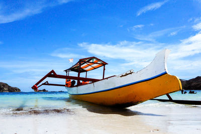 Fishing boat on beach against sky