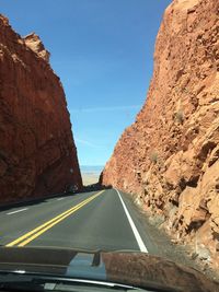 Road amidst rocks seen through car windshield