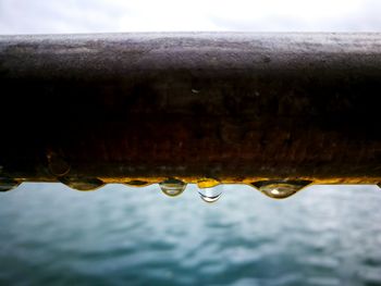 Close-up of raindrops on water against sky