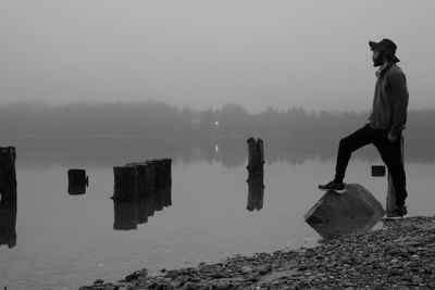 Full length of man standing by lakeshore against sky