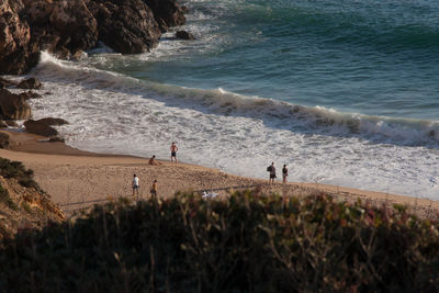 People walking on beach by sea against sky