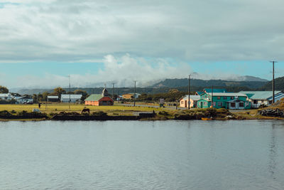 Houses by lake against sky