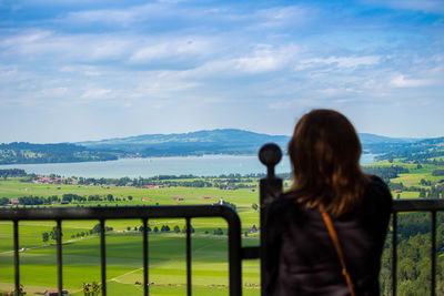 Rear view of woman standing on mountain against sky