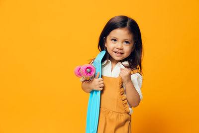 Portrait of young woman holding gift against yellow background