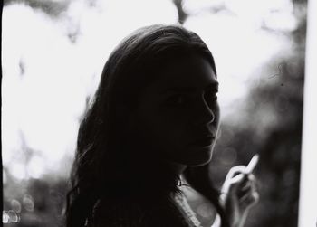 Close-up portrait of young woman holding cigarette