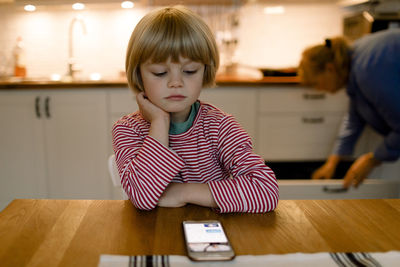 Boy looking at smart phone while grandmother in background