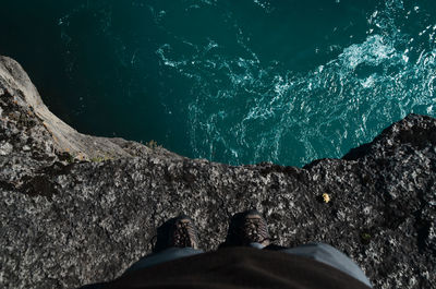 Low section of person on rock by sea