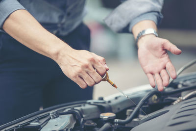 Midsection of man examining car engine