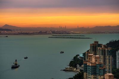 High angle view of buildings by sea against sky during sunset
