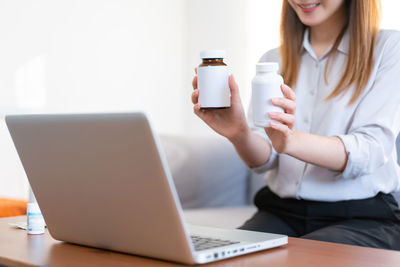 Midsection of woman using smart phone on table