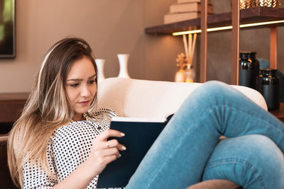 Young woman using mobile phone while sitting on sofa at home