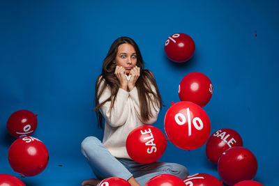 Portrait of woman with balloons against blue background