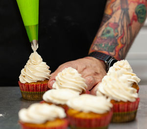 Close-up of man preparing cupcake on table