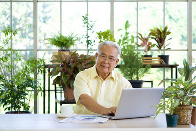 Portrait of senior man using laptop at greenhouse