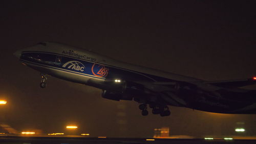 Low angle view of illuminated airplane against sky at night