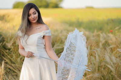 Portrait of smiling young woman standing on field