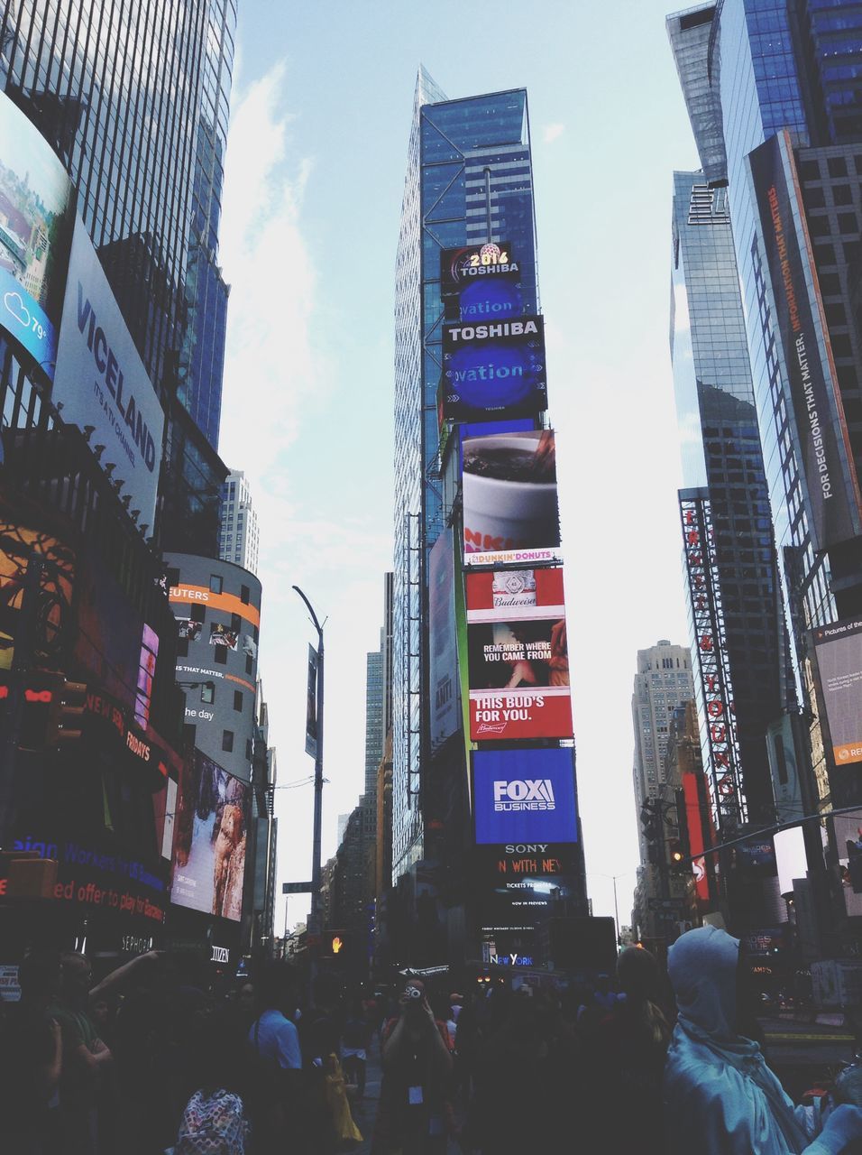 building exterior, architecture, city, built structure, city life, text, street, large group of people, communication, skyscraper, low angle view, city street, tall - high, western script, tower, building, office building, car, modern