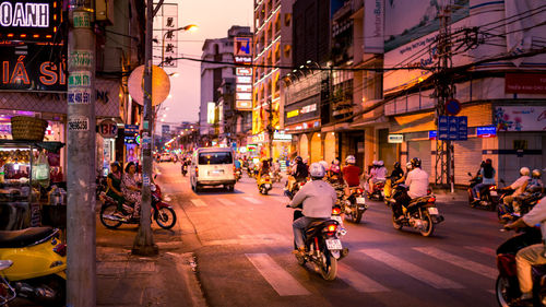 People riding motor scooters on street in city