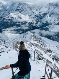 High angle view of woman standing on snow covered land against mountains