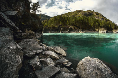 Scenic view of sea by mountain against sky