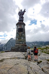 Hikers standing on monument at great st bernard pass