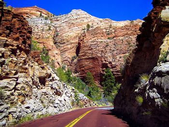 Road amidst trees against mountain