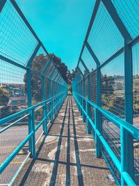 Empty footbridge against clear blue sky