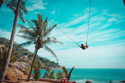 Rear view of woman swinging by sea