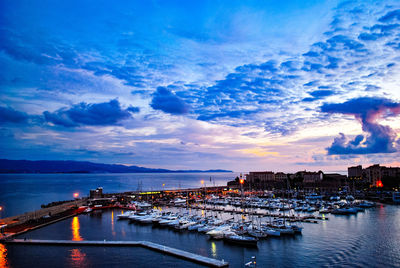 Boats moored in harbor at sunset