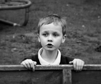 Cute boy standing by fence at playground