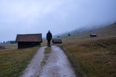 Rear view of man walking on field against sky