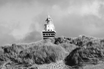 Lighthouse on field against sky