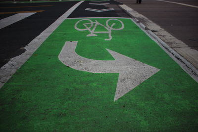 High angle view of arrow and bicycle lane sign on road