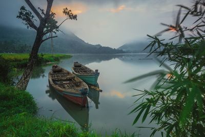 Boat moored on lake against sky