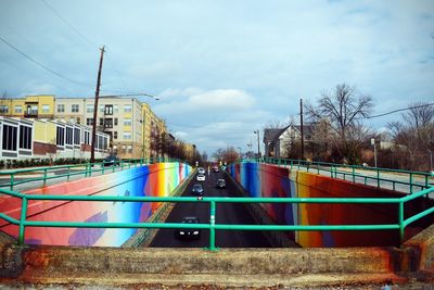 Multi colored buildings by canal against sky in city