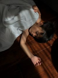 High angle view of boy sleeping on floorboard