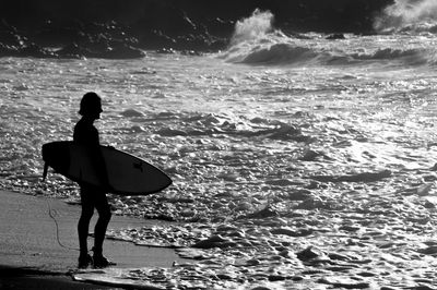 Rear view of woman standing in sea against sky