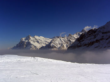 Scenic view of snow covered mountains against clear blue sky